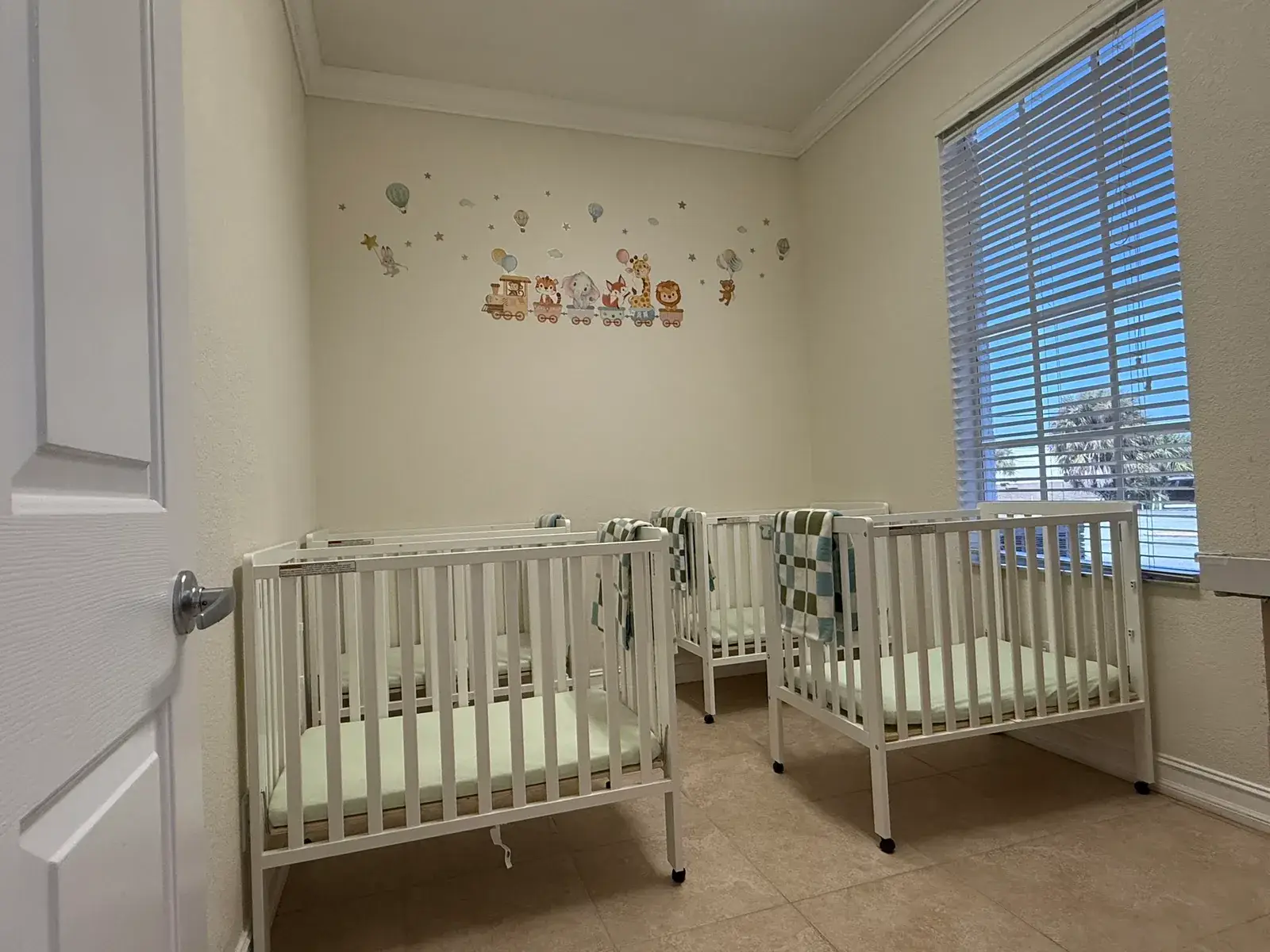 Cribs made up for naptime in the infant room at Ellie's World PPEC in Port Charlotte, Florida