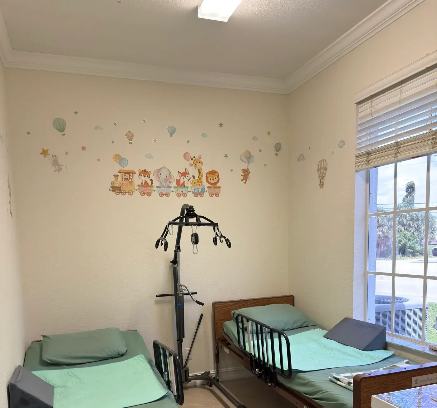 Hospital-style beds and a patient lift in the rest area at Ellie's World PPEC in Port Charlotte, Florida