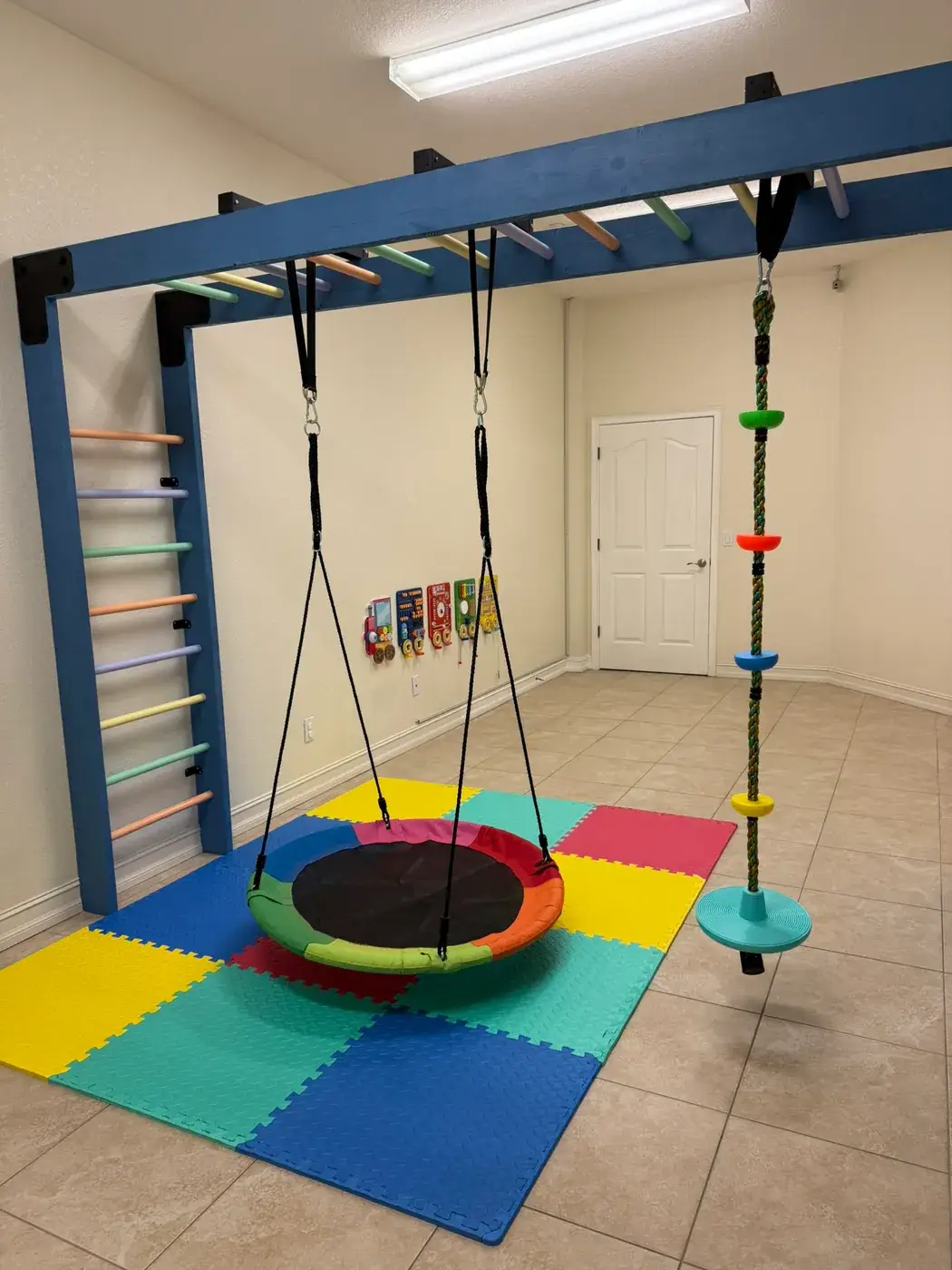 The sensory gym with a platform swing, climbing rope and wall ladder at Ellie's World PPEC in Port Charlotte, Florida